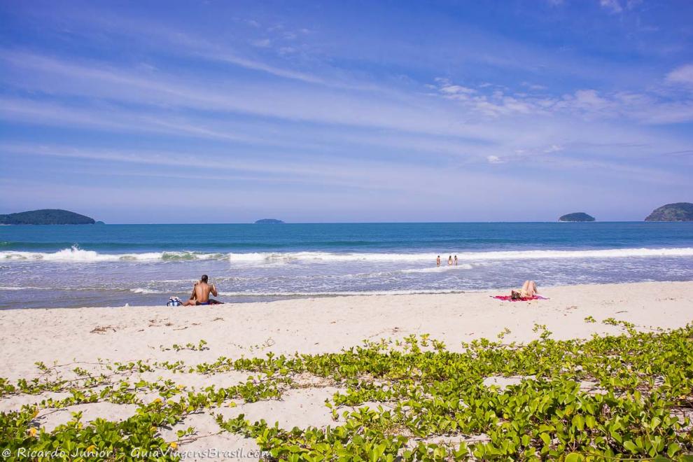 Imagem de duas pessoas nas areias da praia curtindo um dia maravilhoso.